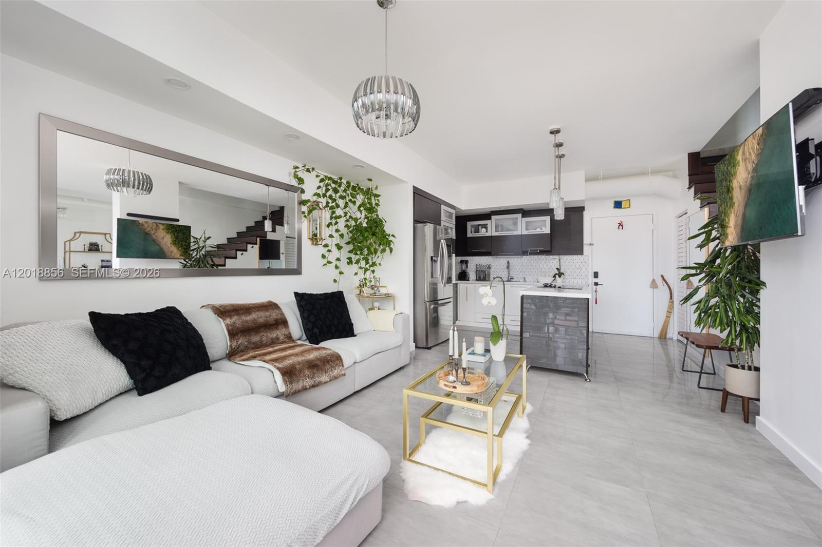 A modern living room and kitchen area features a grey sectional, gold coffee table, and plants — 690 SW 1st Ct, Miami FL 33130, MIAMI, FL
