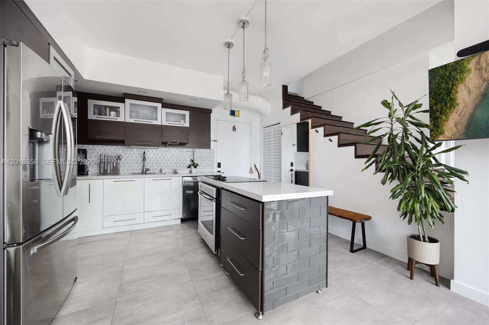A modern kitchen features a central island, dark wood cabinetry, white lower cabinets, and stairs — 690 SW 1st Ct, Miami FL 33130, MIAMI, FL