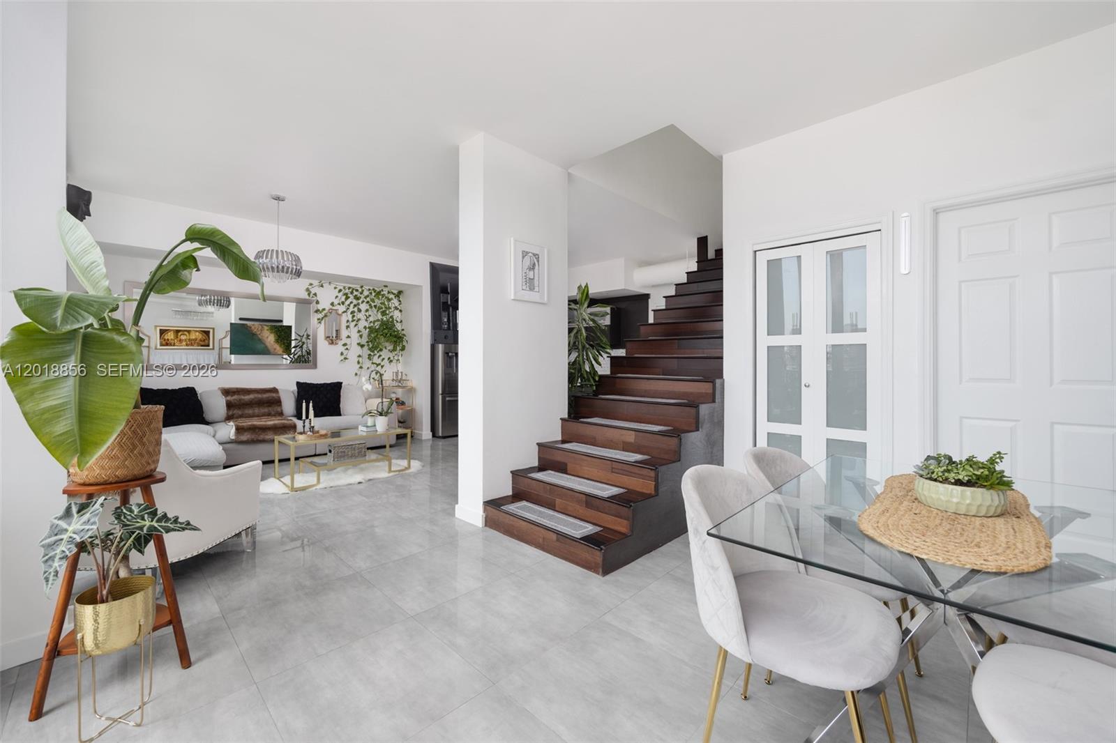 A modern living and dining area features tile floors, a wooden staircase, and white walls — 690 SW 1st Ct, Miami FL 33130, MIAMI, FL