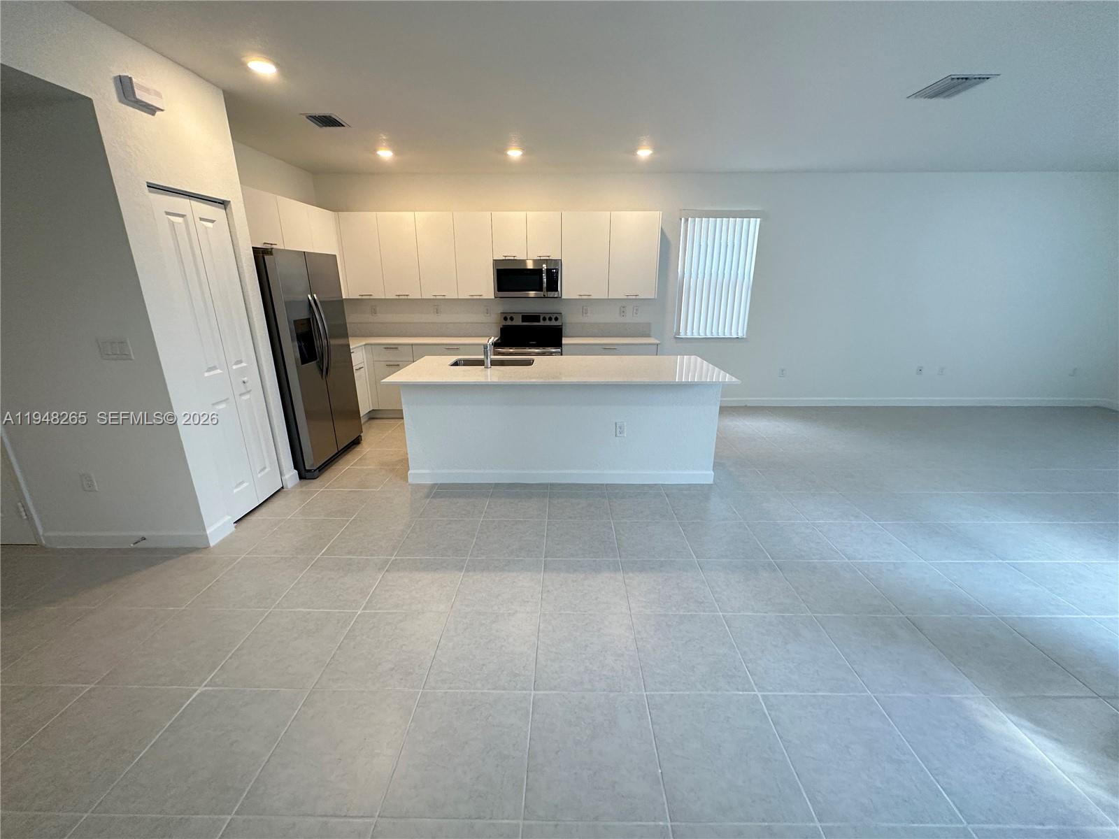 A modern kitchen features white cabinetry, stainless steel appliances, and a central island — 2382 NW 131st Cir, Miami FL 33167, MIAMI, FL