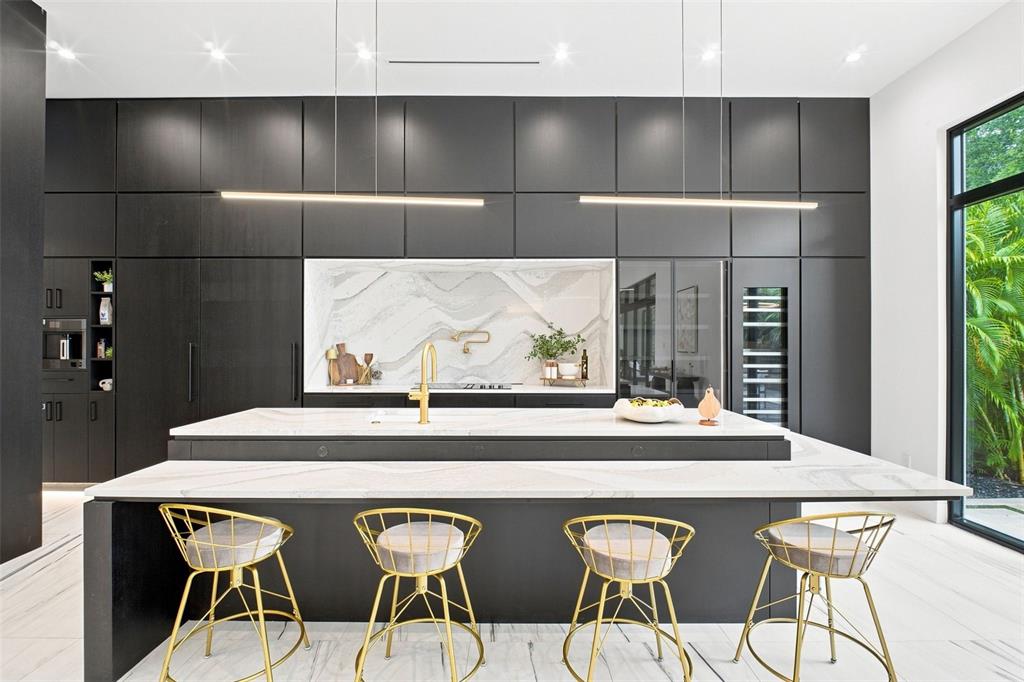 A modern kitchen features dark cabinetry, a marble-topped island with gold stools, and linear lighting — 1076 SNELL ISLE BOULEVARD NE, ST PETERSBURG, FL