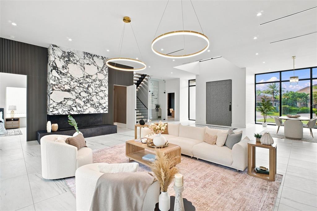 A modern living room features a large marble fireplace, circular pendant lights, and white tile — 1076 SNELL ISLE BOULEVARD NE, ST PETERSBURG, FL