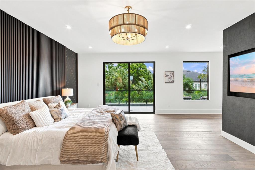 A bedroom features a slatted accent wall, a drum chandelier, and a view of greenery — 1076 SNELL ISLE BOULEVARD NE, ST PETERSBURG, FL