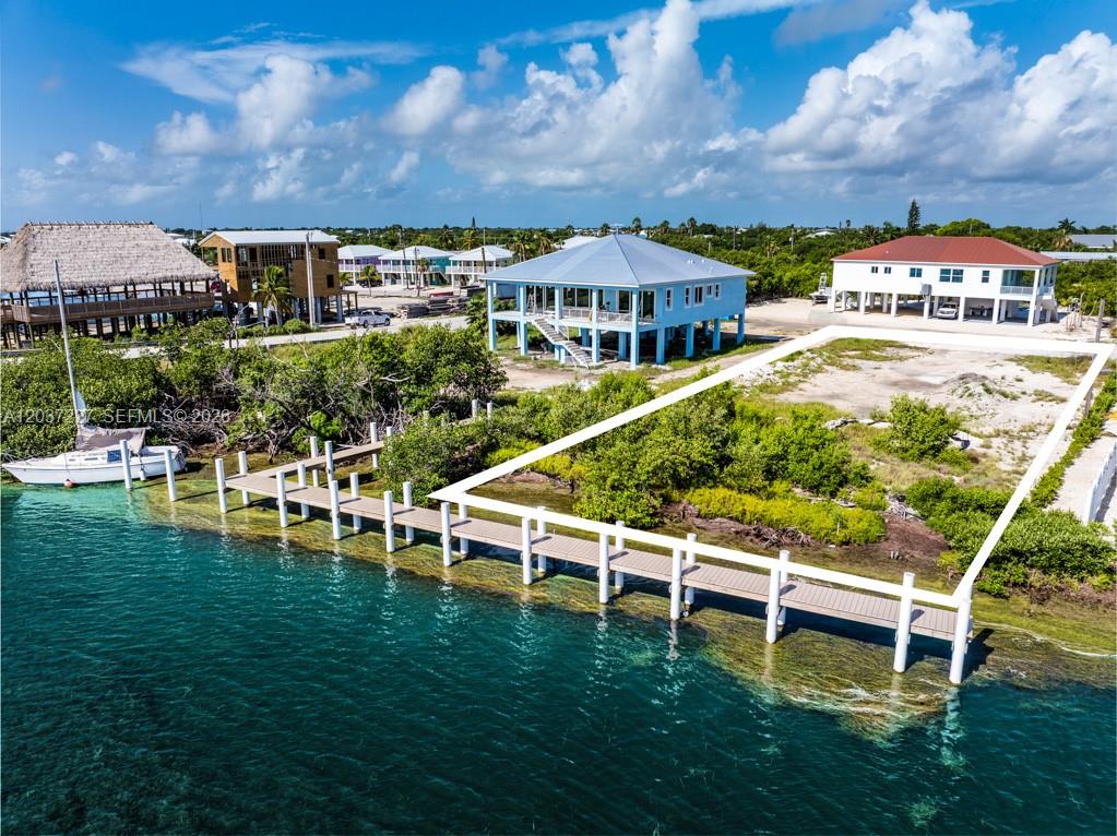 An aerial view shows a vacant waterfront lot with a private dock and nearby houses — 30988 Witters Ln, Big Pine FL 33043, BIG PINE, FL