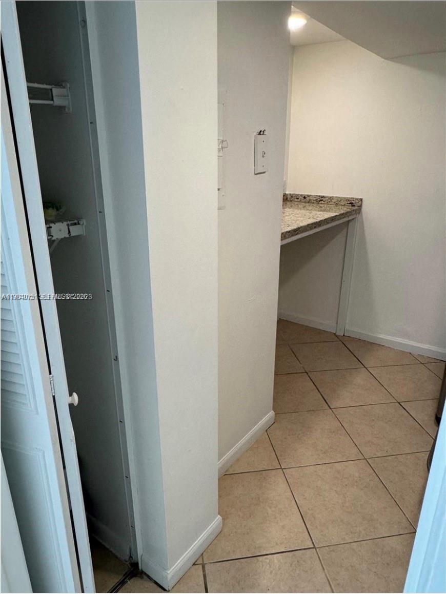 A small room features tan tile flooring, a granite countertop, and a white closet door — 20850 San Simeon Way # 5, Miami FL 33179, MIAMI, FL