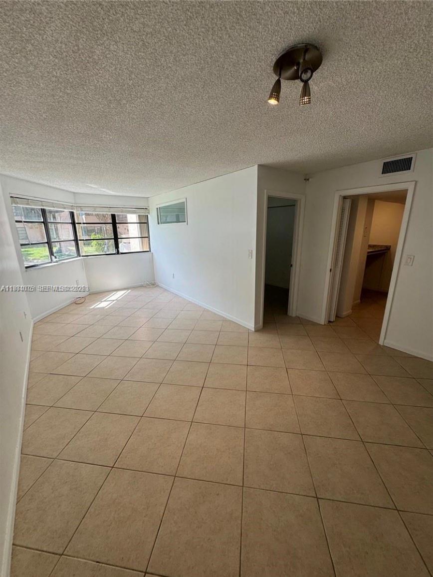 An empty room with beige tile flooring, white walls, and a large window — 20850 San Simeon Way # 5, Miami FL 33179, MIAMI, FL