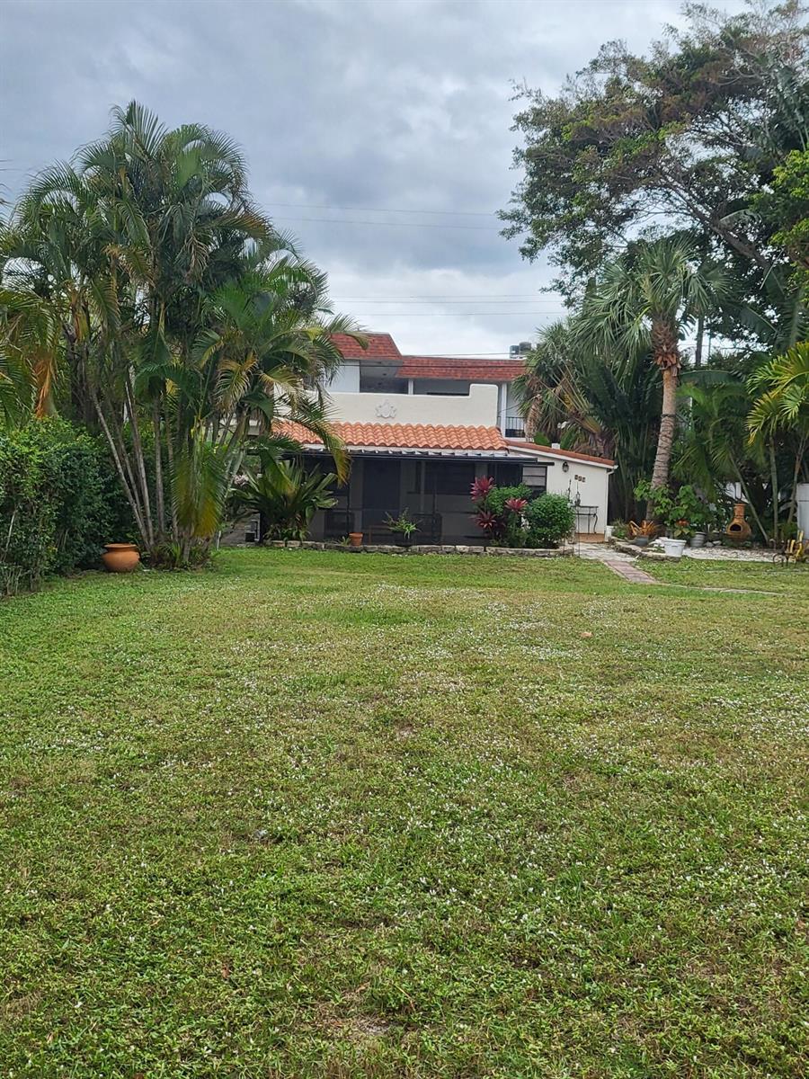 A single-story house with a tiled roof and a covered patio sits behind a lawn — 927 S Palmway, FL 33460, FL