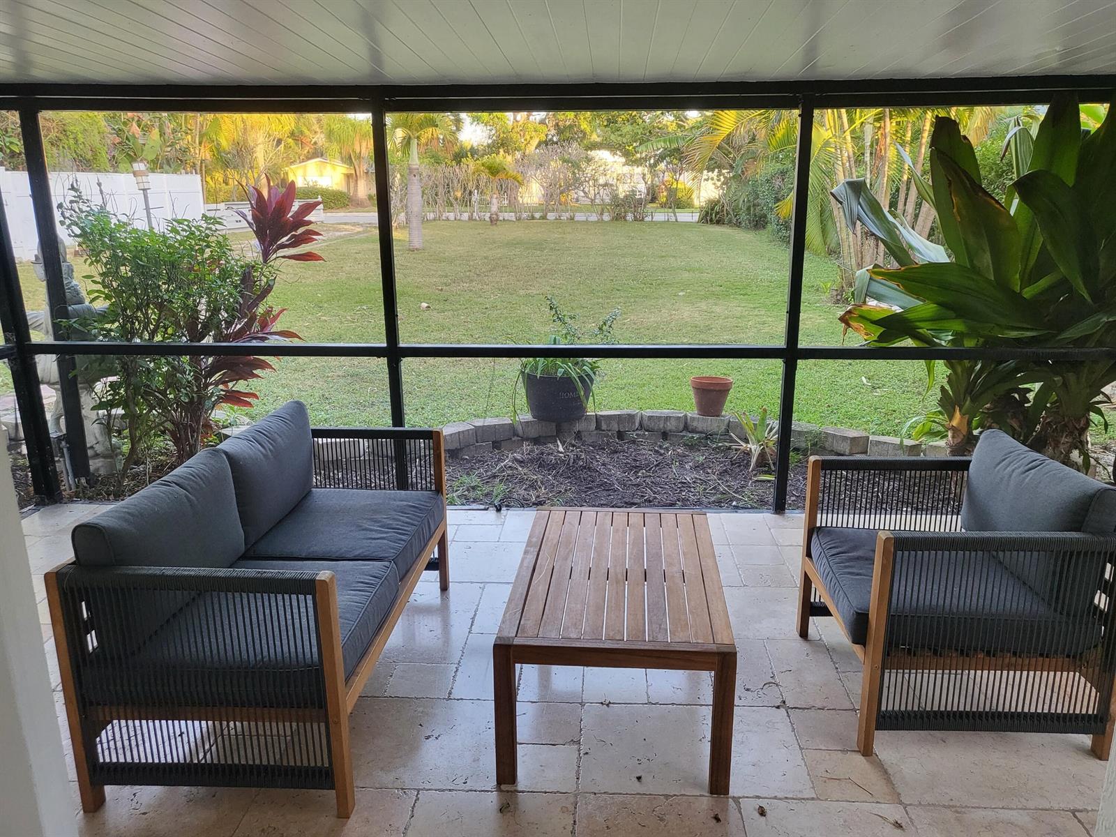A screened-in patio features outdoor furniture, stone tile flooring, and a view of the yard — 927 S Palmway, FL 33460, FL