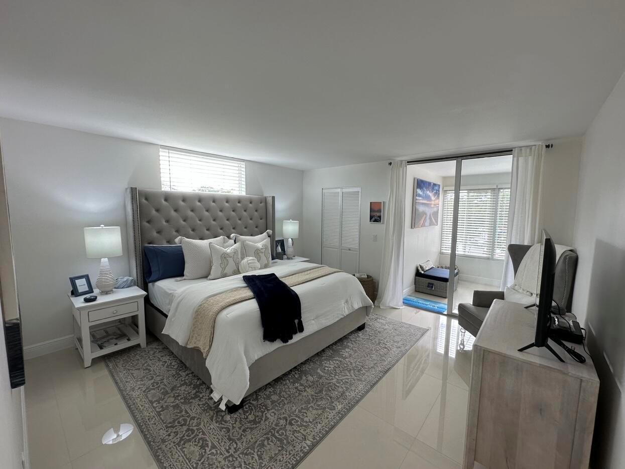 A bedroom features a tufted headboard, a patterned area rug, and a sliding glass door — 14773 Cumberland Drive # 3010, Delray Beach FL 33446, DELRAY BEACH, FL