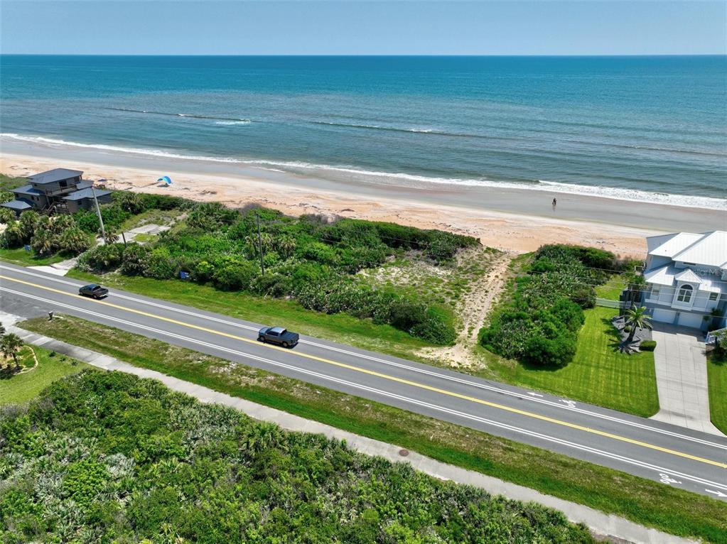 An aerial view shows a coastal road separating a vacant lot from the ocean beach — 3502 N OCEAN SHORE BOULEVARD, PALM COAST, FL