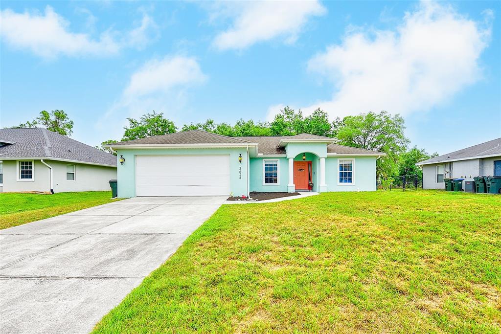 A single-story house with a light blue exterior, white garage door, and a sunset sky — 2624 SHALIMAR TERRACE, NORTH PORT, FL