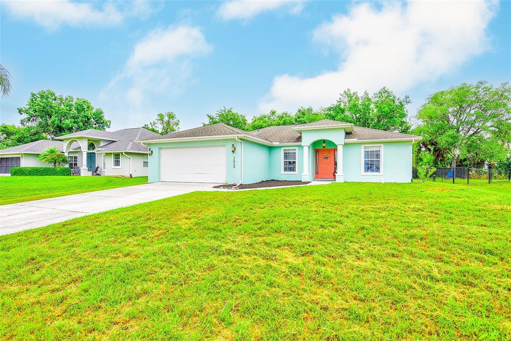 A light blue single-story house with a white garage door and an orange front door — 2624 SHALIMAR TERRACE, NORTH PORT, FL