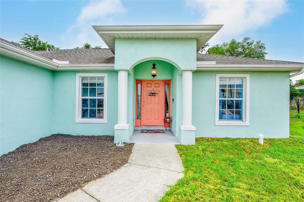 A light blue single-story house with a white garage and an orange front door — 2624 SHALIMAR TERRACE, NORTH PORT, FL