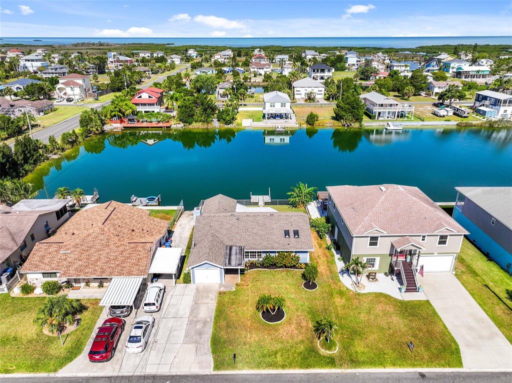 An aerial view shows three waterfront houses with driveways, lawns, and a canal — 3345 POINSETTIA DRIVE, HERNANDO BEACH, FL