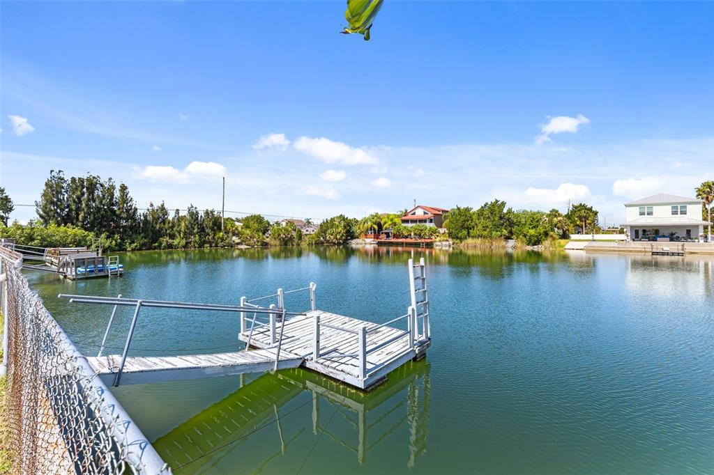 A wooden dock extends into a calm canal surrounded by trees and residential houses — 3345 POINSETTIA DRIVE, HERNANDO BEACH, FL