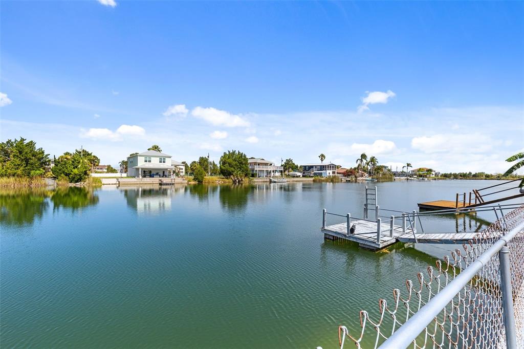 A view of a calm canal with a wooden dock and waterfront houses in the distance — 3345 POINSETTIA DRIVE, HERNANDO BEACH, FL
