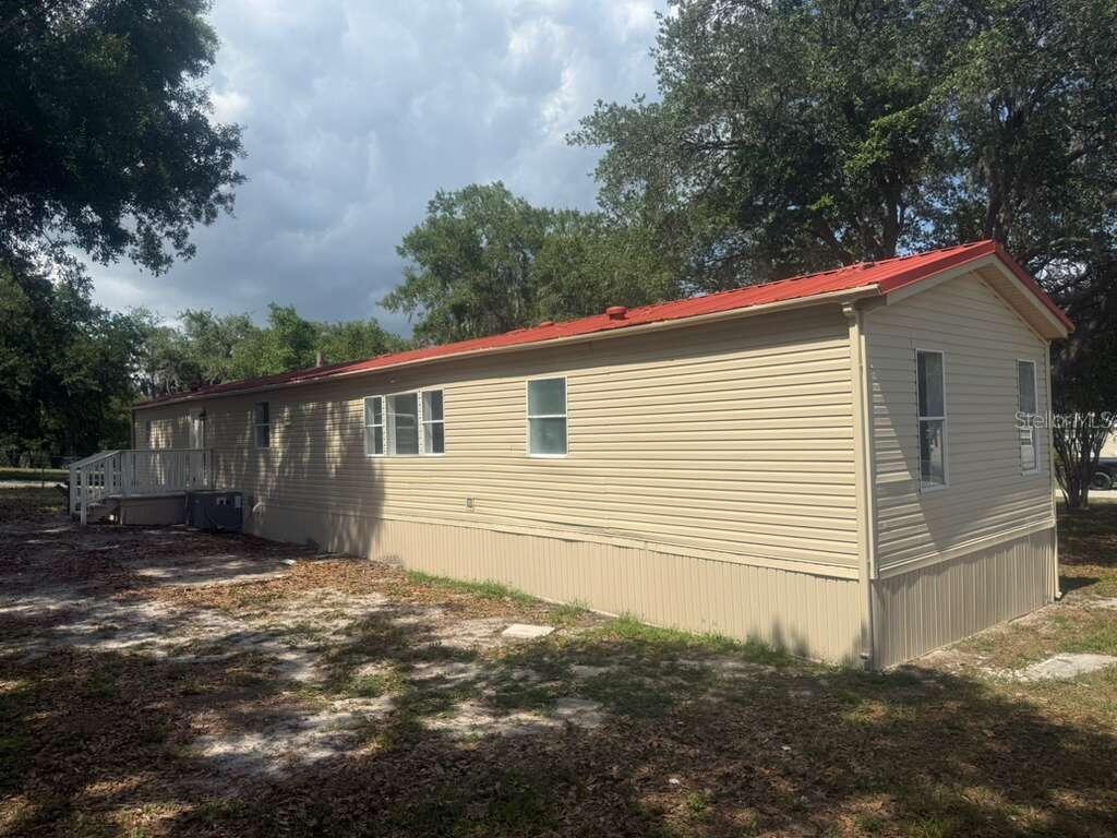 A tan mobile home with a red metal roof sits on a grassy lot — 1650 BELMONT AVENUE UNIT 29, MULBERRY, FL
