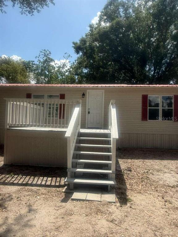 A single-story mobile home features a wooden deck with stairs leading to the front door — 1650 BELMONT AVENUE UNIT 29, MULBERRY, FL