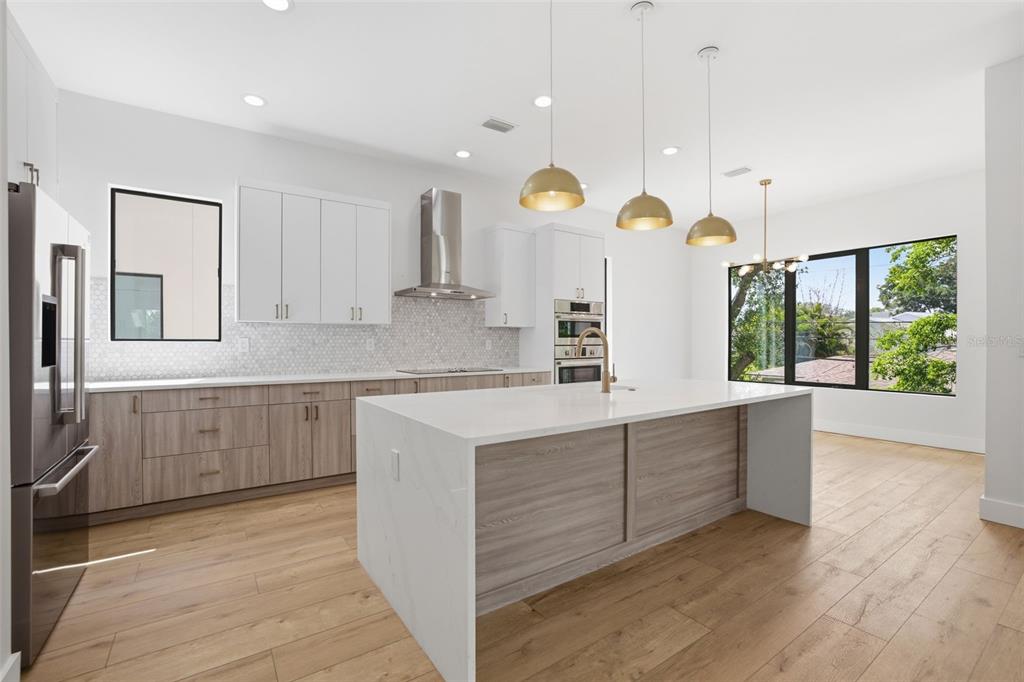 An open-concept kitchen and living area with a central island, white cabinetry, and wood flooring — 1943 SHORE ACRES BOULEVARD NE, ST PETERSBURG, FL