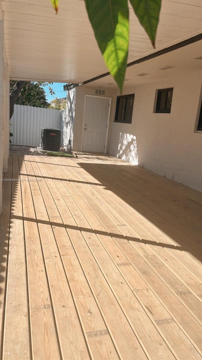 A wooden deck extends from a white house exterior under a covered patio roof — SWEETWATER, FL