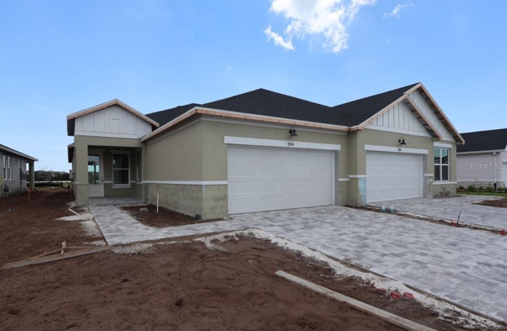 A newly constructed duplex with two garage doors, light-colored stucco walls, and paved driveways — 2845 MARRAKESH LANE, SARASOTA, FL