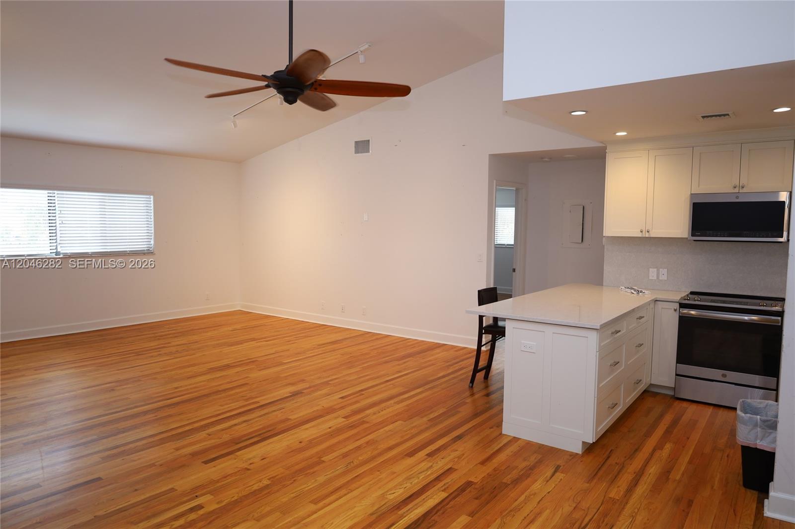 An open-concept living area features hardwood floors, a vaulted ceiling, and an adjacent kitchen — 340 Conniston Rd # 340, West Palm Beach FL 33405, WEST PALM BEACH, FL