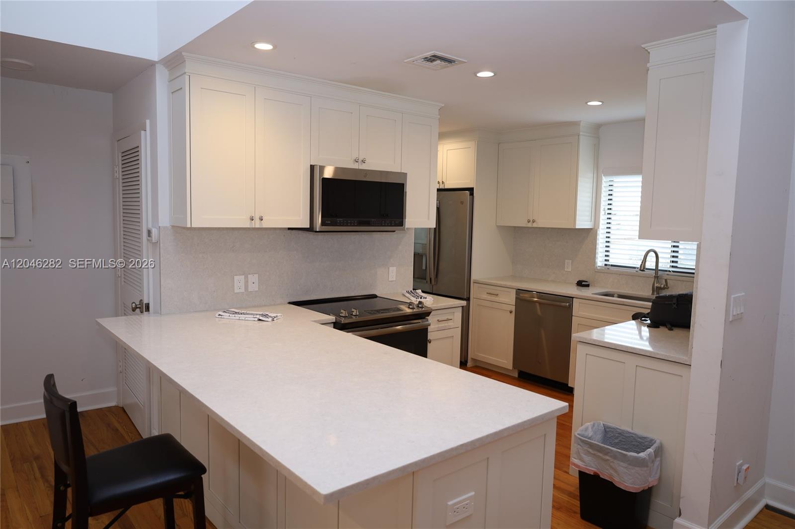 A kitchen features white cabinets, stainless steel appliances, and a large white countertop peninsula — 340 Conniston Rd # 340, West Palm Beach FL 33405, WEST PALM BEACH, FL