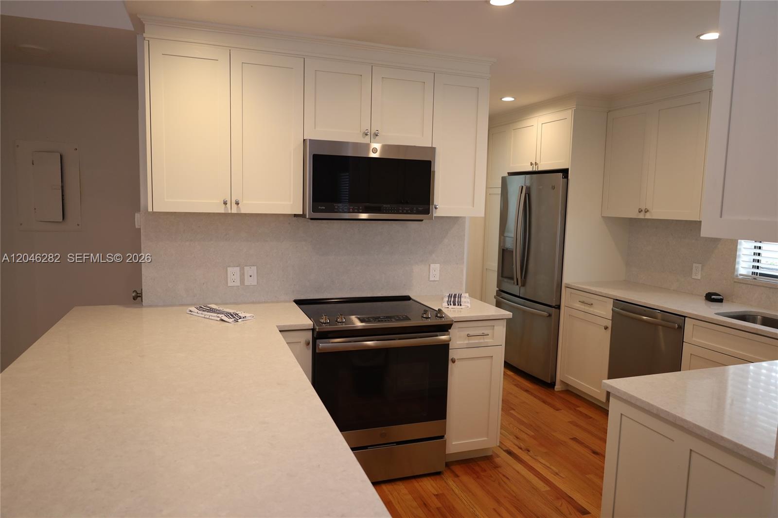 A kitchen features white cabinets, stainless steel appliances, and light-colored countertops over hardwood floors — 340 Conniston Rd # 340, West Palm Beach FL 33405, WEST PALM BEACH, FL
