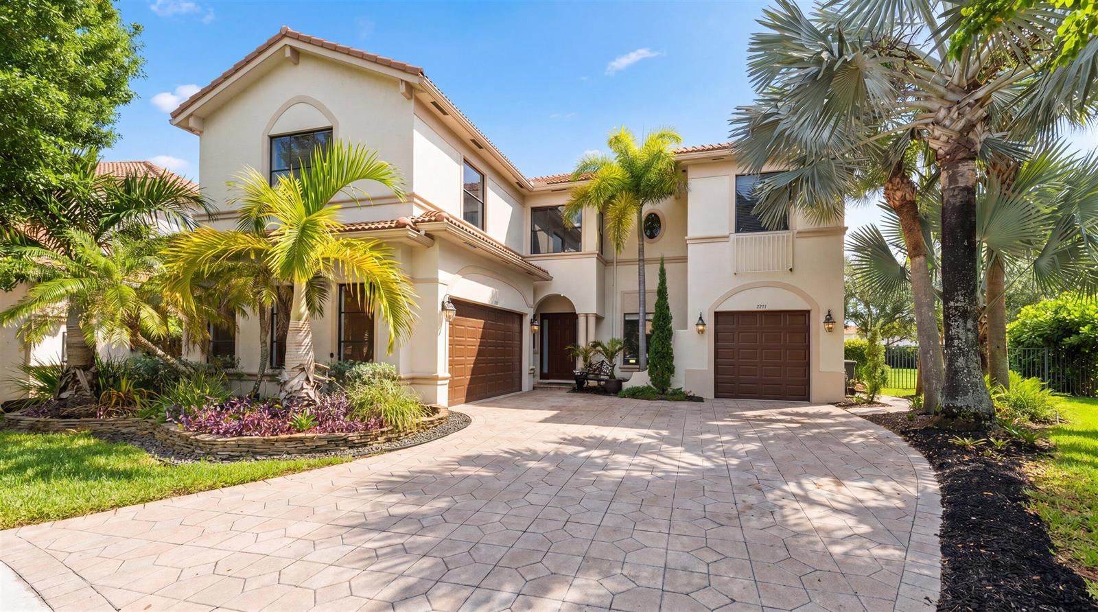 A two-story stucco house features a paved driveway, two garage doors, and several palm trees — 1215 Creekside Drive, Wellington FL 33414, WELLINGTON, FL