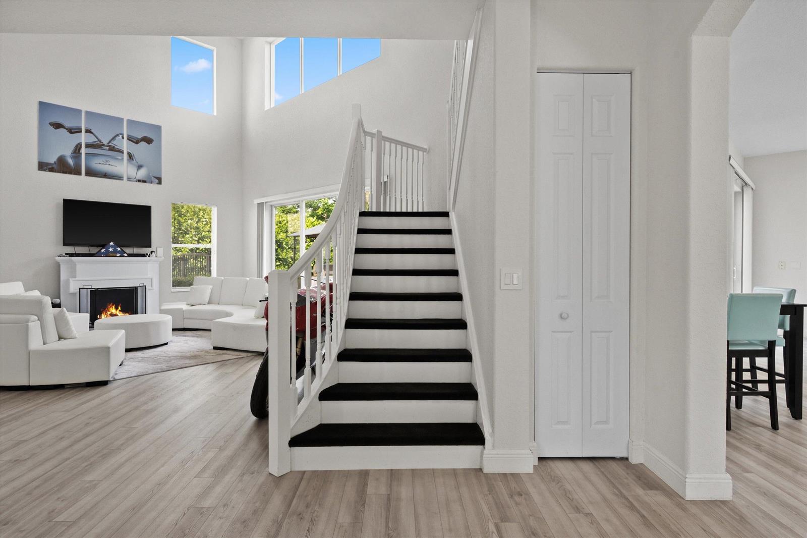 A living room with a fireplace and staircase features white walls and light wood flooring — 1215 Creekside Drive, Wellington FL 33414, WELLINGTON, FL