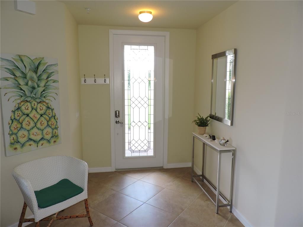 An entryway features tile flooring, a white front door with glass, a mirror, and furniture — 20201 RAGAZZA CIRCLE UNIT 102, VENICE, FL
