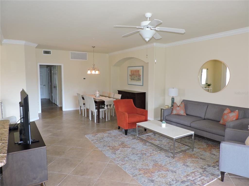 An open-concept living and dining area features tile flooring, a ceiling fan, and neutral walls — 20201 RAGAZZA CIRCLE UNIT 102, VENICE, FL