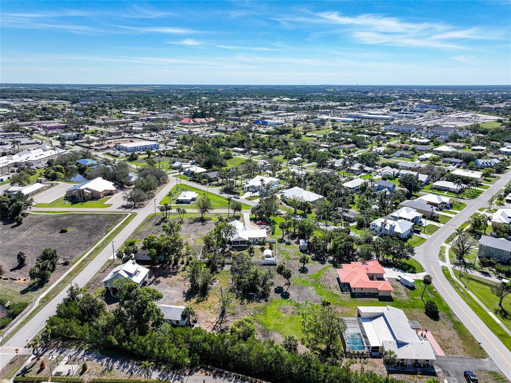 An aerial view shows a suburban neighborhood with houses, roads, and surrounding green space — 479 GILL STREET, PUNTA GORDA, FL