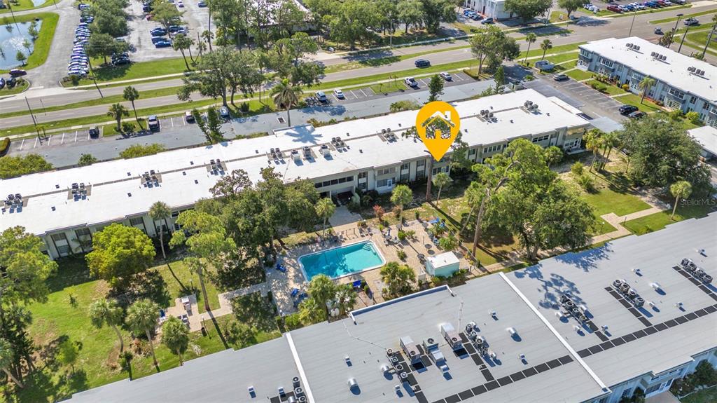 An aerial view shows a multi-story apartment complex with a swimming pool and parking lots — 2437 HARBOR BOULEVARD UNIT 114, PORT CHARLOTTE, FL