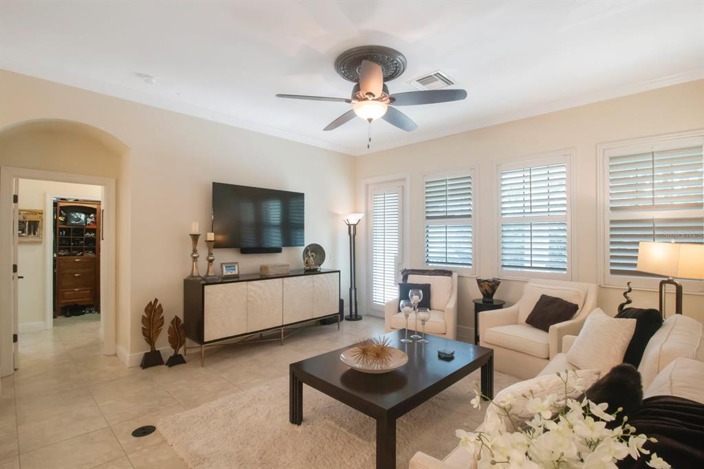 A living room with tile floors, a ceiling fan, a television, and white armchairs — 4884 YACHT CLUB DRIVE, TAMPA, FL