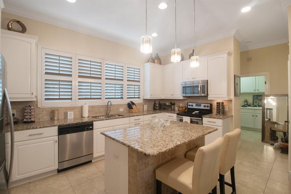 A kitchen with white cabinets, granite countertops, a center island, and stainless steel appliances — 4884 YACHT CLUB DRIVE, TAMPA, FL
