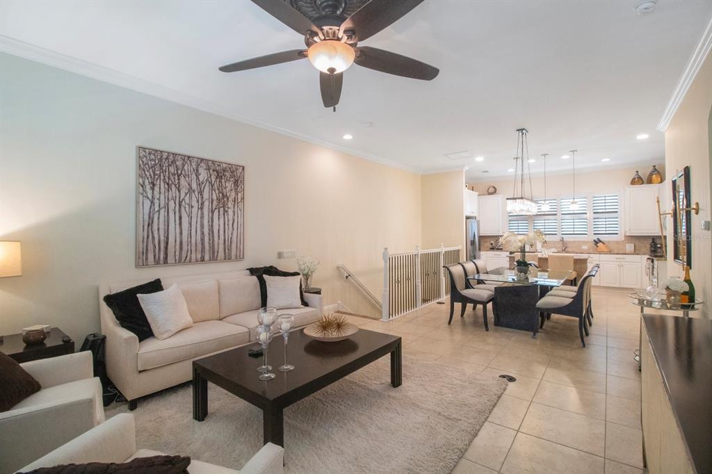 An open-concept living and dining area features a sofa, coffee table, and kitchen with white cabinetry — 4884 YACHT CLUB DRIVE, TAMPA, FL