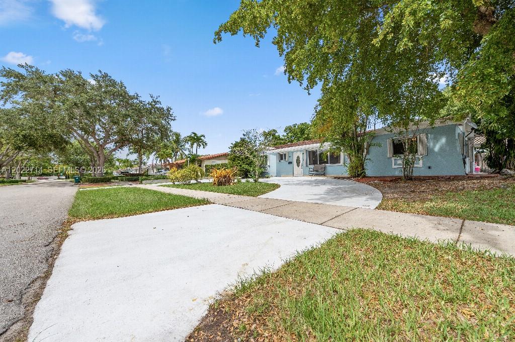 A light blue single-story house features a curved concrete driveway and mature shade trees — 7311 SW 139th Ave, Miami FL 33183, MIAMI, FL