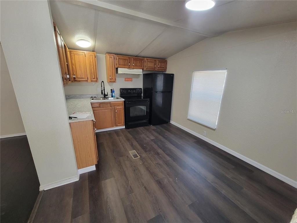 A kitchen features wood cabinets, black appliances, and dark wood-look flooring — 16625 NE 2ND STREET ROAD, SILVER SPRINGS, FL
