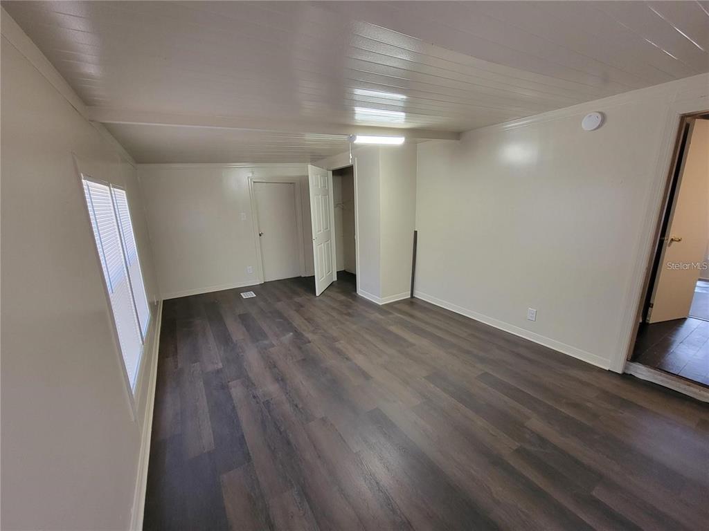 An empty bedroom features wood-look flooring, white walls, a ceiling light, and a closet — 16625 NE 2ND STREET ROAD, SILVER SPRINGS, FL