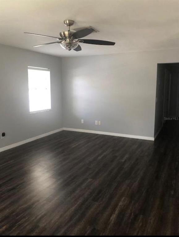 An empty room with light gray walls, dark wood-look flooring, and a ceiling fan — 6910 S TRASK STREET, TAMPA, FL