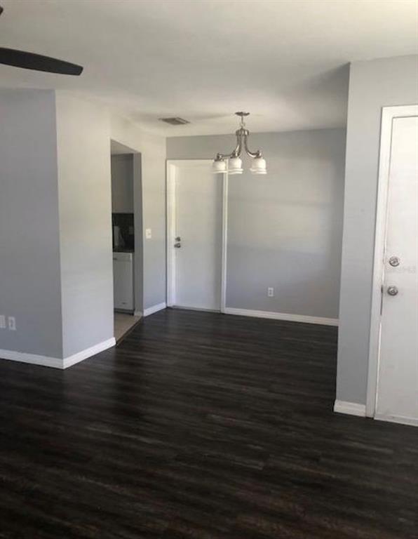 A dining area with dark wood-look flooring, light gray walls, and a hanging light fixture — 6910 S TRASK STREET, TAMPA, FL