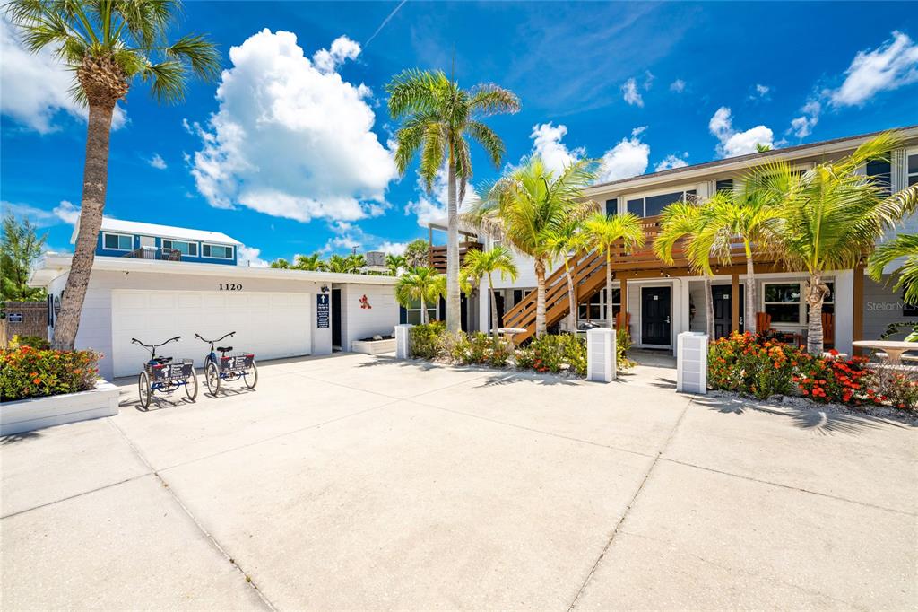 A two-story building with a concrete driveway, palm trees, and bicycles parked in front — 1120 GULF BOULEVARD, ENGLEWOOD, FL