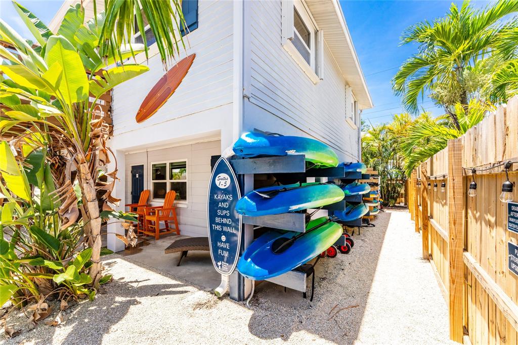 An exterior view shows a building with a kayak rack and a surfboard wall decoration — 1120 GULF BOULEVARD, ENGLEWOOD, FL