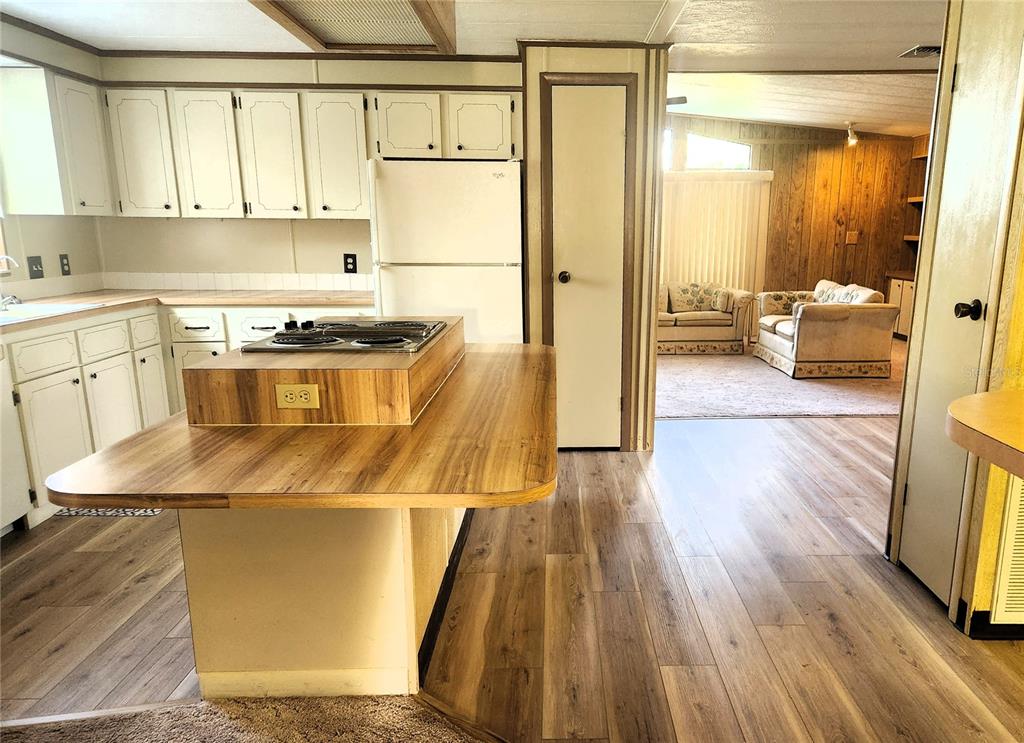 A kitchen with wood-look flooring and a central island features white cabinets and appliances — 151 LAZY RIVER ROAD, NORTH PORT, FL