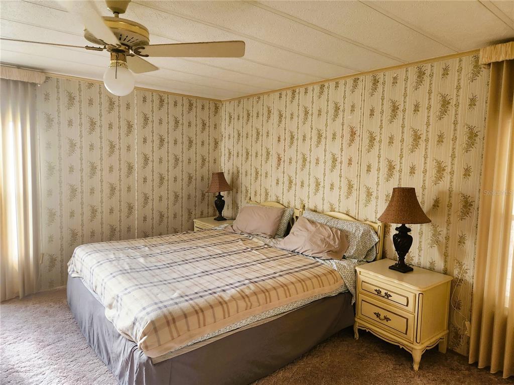A bedroom features a bed with a plaid comforter, floral wallpaper, and a ceiling fan — 151 LAZY RIVER ROAD, NORTH PORT, FL
