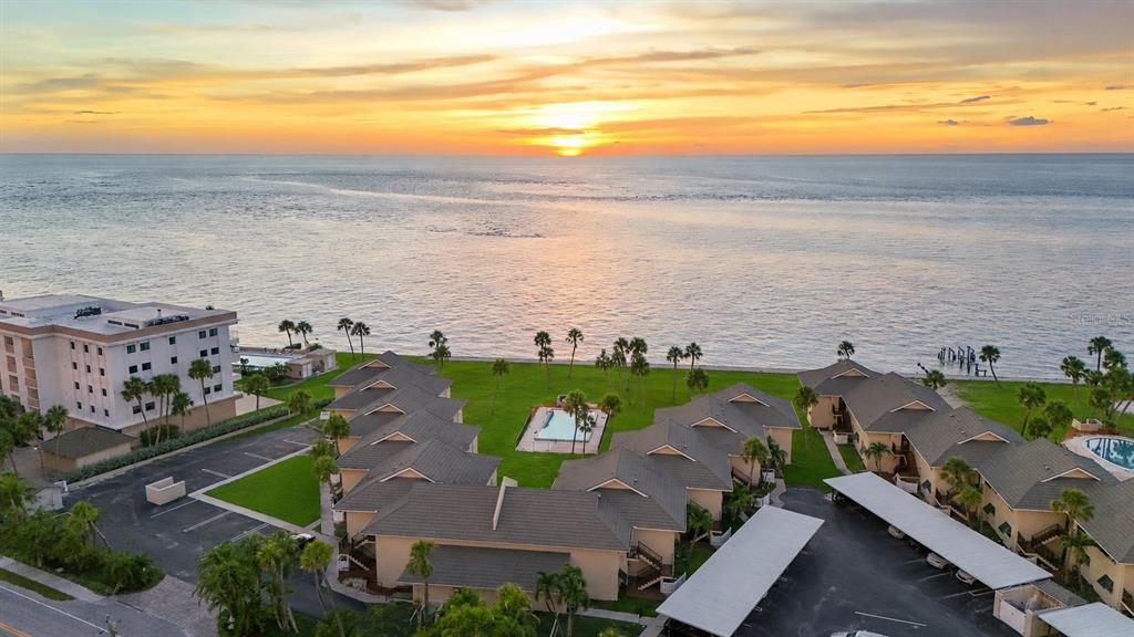 An aerial view shows a waterfront residential complex with a pool at sunset — 4660 OCEAN BOULEVARD UNIT Q, SARASOTA, FL
