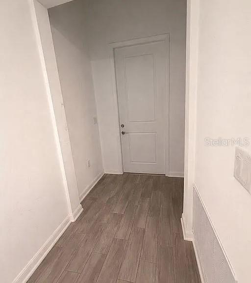 A narrow hallway with light-colored walls and wood-look tile flooring leads to a closed door — 1104 SAND TRAP COURT, DAYTONA BEACH, FL