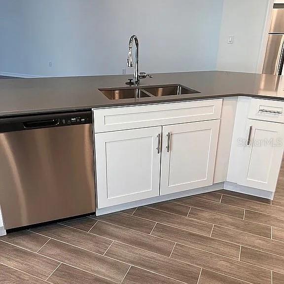 A kitchen island features a stainless steel dishwasher, white cabinets, and a dark countertop — 1104 SAND TRAP COURT, DAYTONA BEACH, FL