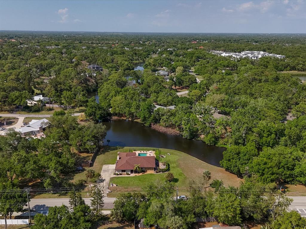 An aerial view shows a house with a pool situated next to a small lake — 3927 DESOTO ROAD, SARASOTA, FL